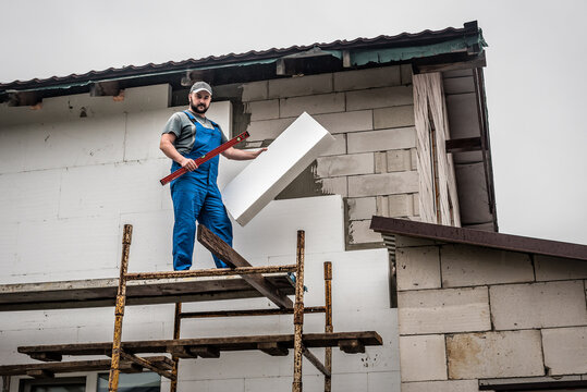 Fachbetriebarbeiter, der Dämmmaterial in Hand hält und Fassade erneuert